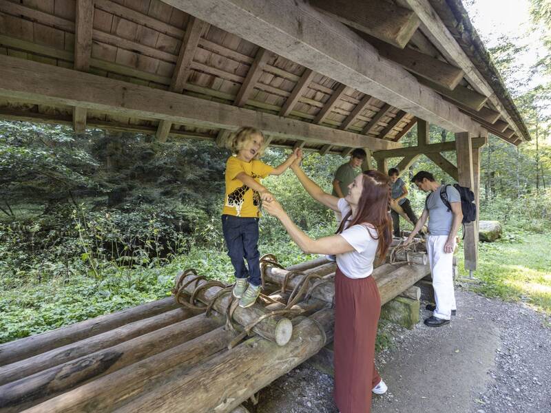 Eine Familie steht an einem überdachten Floß. Die Kinder stehen darauf.